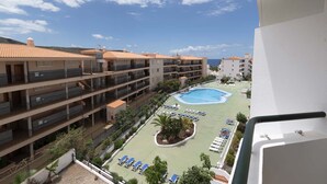 A multi-story hotel with a swimming pool, outdoor seating, and a view of the sea. - Summerland 5 - 1 bedroom with terrace and pool view (Los Cristianos)