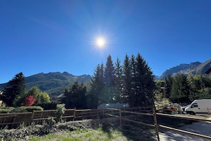 Un paysage montagneux, avec un ciel dégagé, une clôture en bois et un fourgon blanc garé près d’un bâtiment.