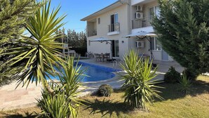 A two-story building with a swimming pool, outdoor seating, and a well-maintained garden.