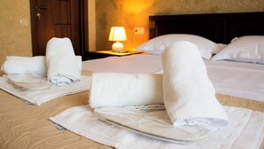 Habitación de hotel con toallas ordenadamente dobladas en las camas, una lámpara de noche y una puerta de madera.