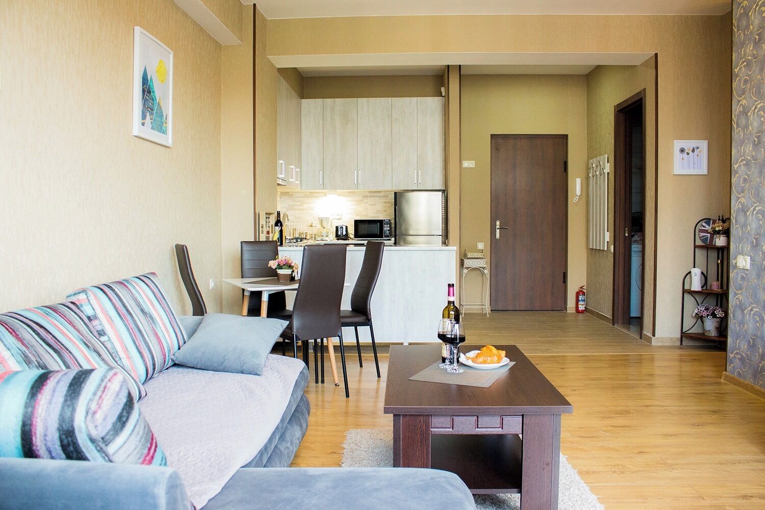 Un salon moderne comprenant un canapé, un coin repas, une cuisine et une porte donnant sur une autre pièce.