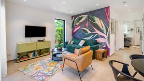 A modern living room with a flat-screen TV, a green sofa, a patterned rug, and a vibrant wall mural. - Apartment Nest20 with Private Terrace and Wi-Fi (Ettenheim)
