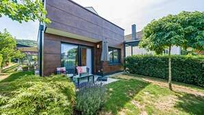 A modern house with a large glass window, a patio with outdoor furniture, and a well-maintained garden. - Apartment Nest20 with Private Terrace and Wi-Fi (Ettenheim)