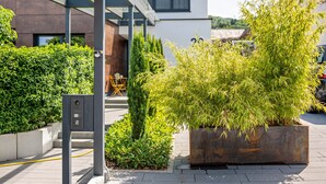 A modern building with a covered outdoor area, potted plants, and a metal structure. - Apartment Nest20 with Private Terrace and Wi-Fi (Ettenheim)
