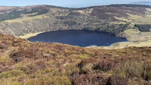 Un lago circondato da colline con rada vegetazione.
