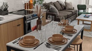 Eine moderne Küche mit einem Esstisch, der für sechs Personen gedeckt ist, einer Couch und einem grünen Sessel in einem Wohnbereich.