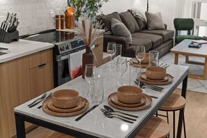 A modern kitchen with a dining table set for six, a sofa, and a green chair in a living area. - Elevated Downtown SLC Stay - Pool + Sauna Retreat (Salt Lake City)