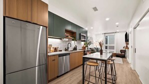 Une cuisine moderne dotée d’appareils électroménagers en acier inoxydable, de meubles en bois et d’un coin bar.