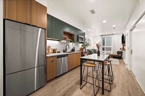 A modern kitchen with stainless steel appliances, wooden cabinets, and a bar area. - Downtown SLC 2BR - Pool + Sauna + Parking (Salt Lake City)