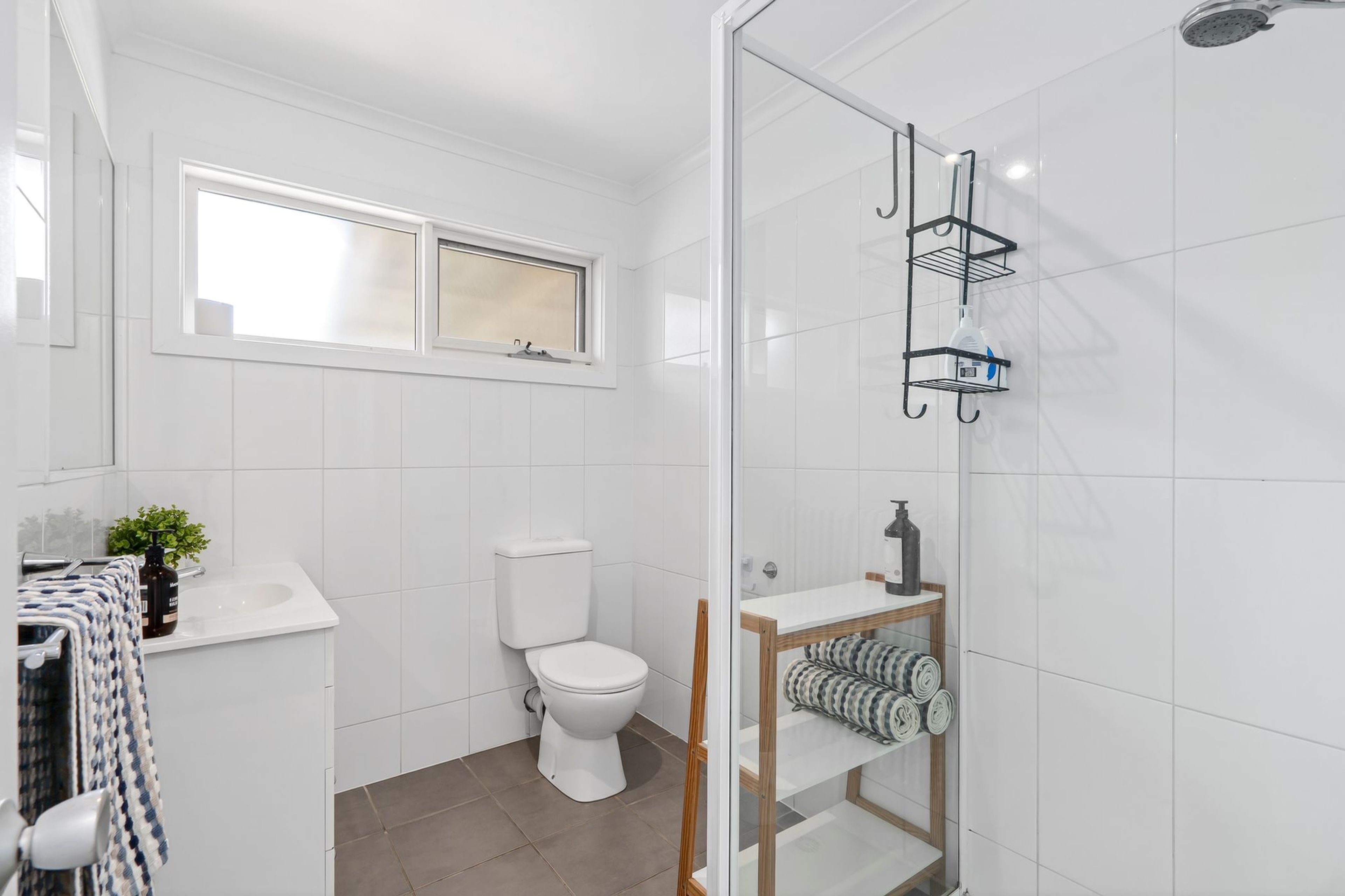 A modern bathroom with a toilet, a shower, and a sink.