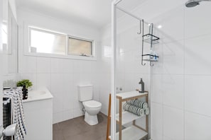 A modern bathroom with a toilet, a shower, and a sink. - Beachfront Apartment at Apollo (Apollo Bay)