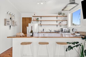 Eine moderne Küche mit weißen Schränken, Holzarbeitsplatten und einer Bar mit Hockern.