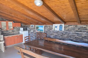 A kitchen with wooden cabinets, a microwave, and a stone wall. - Coastal Bungalow for 5 in Zaton (Zaton)
