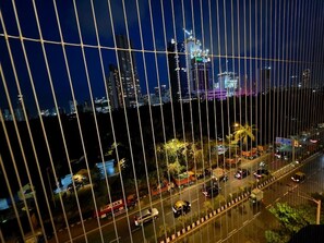 A nighttime cityscape with a view of tall buildings, a busy street with vehicles, and a bridge with vertical lines.