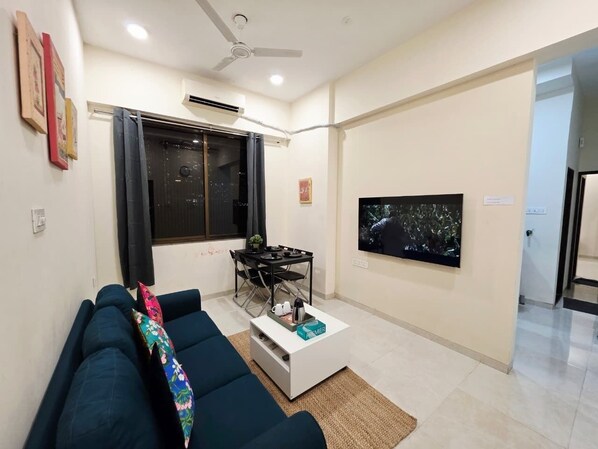 A living room with a sofa, a coffee table, a TV, and a dining area.