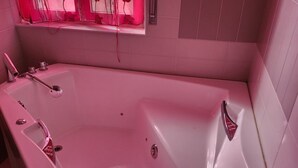 Eine weiße Badewanne mit Duschbrause, Bedienfeld und einem roten Sicherheitsschild.