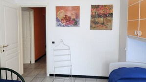 Ein Zimmer mit einem Bett, einem Kleiderhaken und zwei Bildern an der Wand.