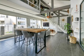 Ein modernes Interieur mit Essbereich, Treppe und großen Fenstern.