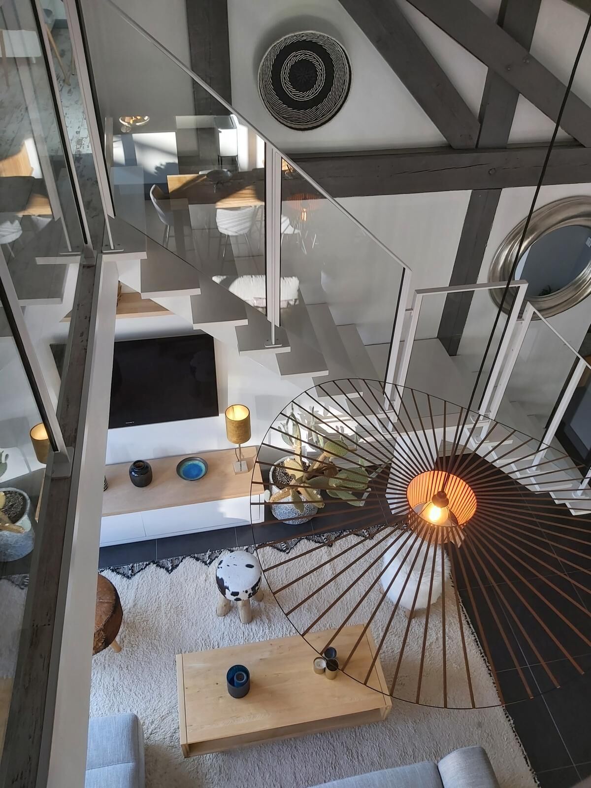 En modern inredning med en spiraltrappa, en taklampa och en rund väggdekoration.