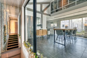 Ein modernes Interieur mit einer Treppe, einem Essbereich mit einem Holztisch und Stühlen sowie einer Küche mit einem Holzschrank.