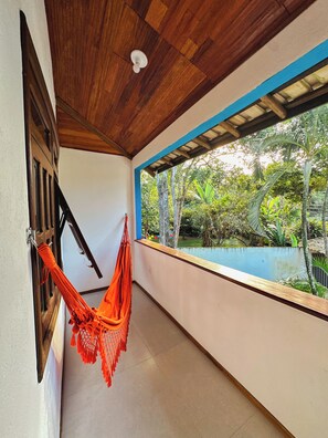A corridor with a wooden ceiling, a hammock, a window with a view of greenery, and a pool. - Arraial d'Ajuda House with private pool near the center (Arraial d'Ajuda)