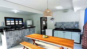 Una cocina moderna con una isla central, banco de madera y lámpara colgante.