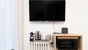 A kitchen with a TV mounted above a countertop, a toaster, a kettle, a microwave, and a radiator. - Suite Élégance at Montparnasse (Paris)