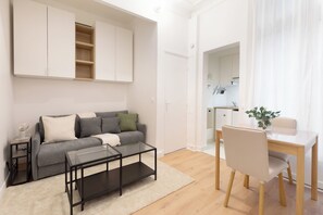 A modern living room with a sofa, coffee table, and dining table with chairs. - Suite Élégance at Montparnasse (Paris)