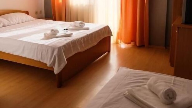 A hotel room with a bed, a wooden floor, an air conditioning unit, and curtains. - Ariston Hotel (Misleshevo)