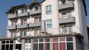 A multi-story building with balconies, large windows, and a visible door. - Ariston Hotel (Misleshevo)