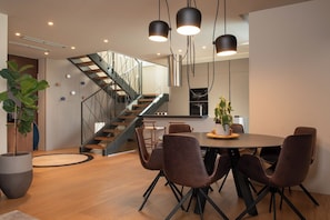 Eine moderne Küche mit Essbereich, einer Treppe und einem großen Kübelpflanze.