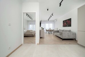 Uma sala de estar moderna com um sofá, uma mesa de jantar com cadeiras e uma área de cozinha.