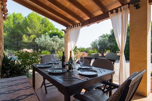 Eine Terrasse im Freien mit Esstisch und Stühlen, umgeben von einer Holzpergola.