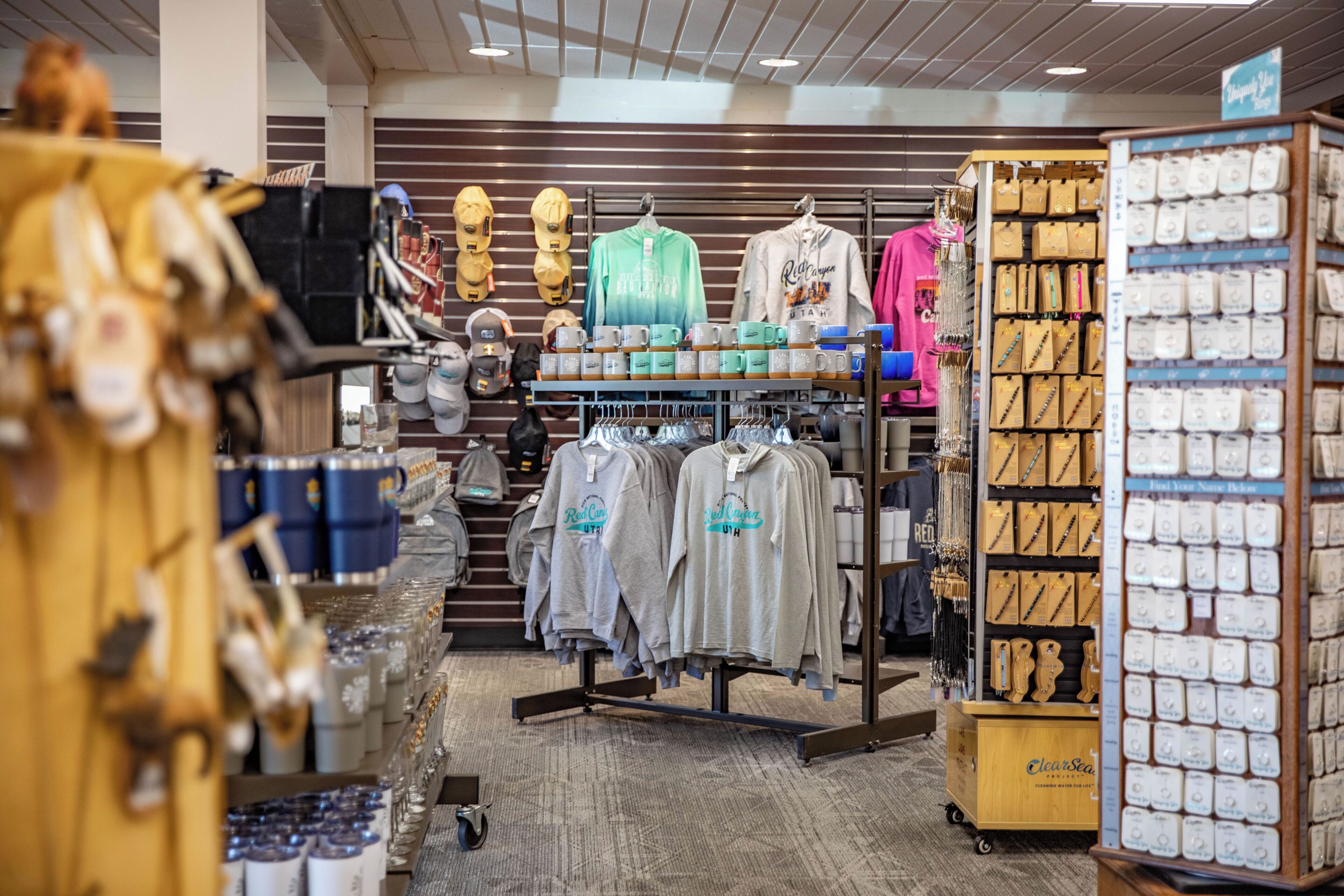A retail store interior with clothing racks, shelves with hats, and a display of jewelry.