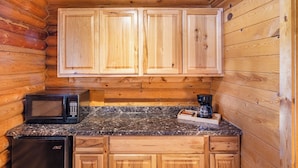 A compact kitchen with wooden cabinets, a microwave, a coffee maker, and a refrigerator. - Red Canyon Village (Panguitch)