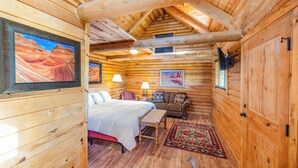 A log cabin interior with a bed, a sofa, a table, and a rug. - Red Canyon Village (Panguitch)