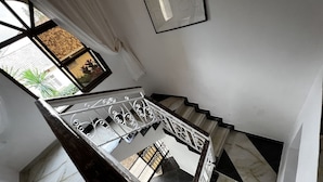 Una escala amb barana metàl·lica, sòl de marbre i vista exterior.