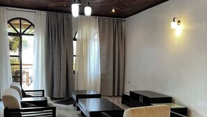 Un saló modern amb sostre de fusta, un conjunt de sofàs, una taula de centre i una làmpada de paret.