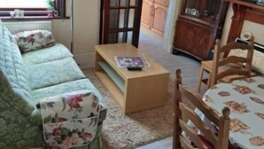 Een woonkamer met een bank, een salontafel en een televisie. Een keuken is zichtbaar door een open deur.