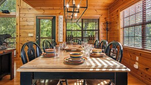 A wooden cabin interior with a dining table set for six, surrounded by chairs, and a chandelier above. - New Listing, Game Room. Hot Tub, Pool Access +Free Attractions! (Sevierville)