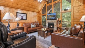A log cabin interior with a fireplace, leather furniture, a television, and a ceiling fan. - New Listing, Game Room. Hot Tub, Pool Access +Free Attractions! (Sevierville)