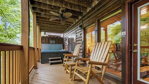 A wooden deck with rocking chairs, a hot tub, and a covered area with a ceiling fan. - New Listing, Game Room. Hot Tub, Pool Access +Free Attractions! (Sevierville)