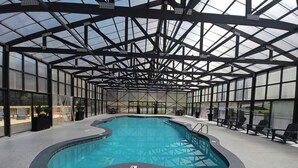 An indoor swimming pool with a glass ceiling, surrounded by lounge chairs and a concrete floor. - New Listing, Game Room. Hot Tub, Pool Access +Free Attractions! (Sevierville)