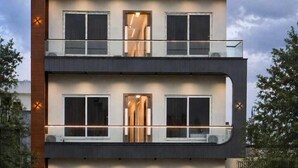 A modern multi-story building with balconies, large windows, and a gated entrance. - The Glam By Sandane Homes (Greater Noida)