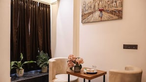 A room with a view of a bridge, a table with a vase of flowers, and two chairs. - The Glam By Sandane Homes (Greater Noida)