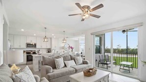 Un salon moderne avec un canapé, une table basse et un balcon aménagé avec des sièges d’extérieur.