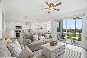 A modern living room with a sofa, coffee table, and a balcony with outdoor seating. - Wellen Park G&CC - 2 bed 2 bath with golf (Venice)
