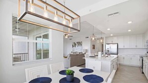Une cuisine moderne avec des armoires blanches, un îlot central et des luminaires suspendus.