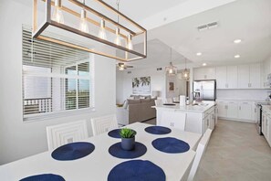 A modern kitchen with white cabinets, a central island, and pendant lighting. - Wellen Park G&CC - 2 bed 2 bath with golf (Venice)