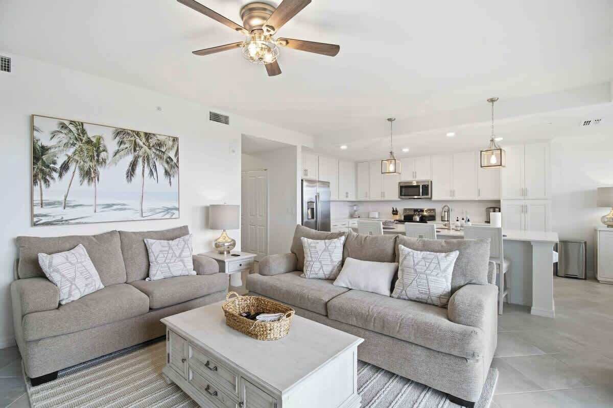 A modern living room with a sofa, coffee table, and a painting of palm trees.